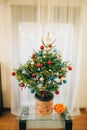 A small Christmas tree in a pot, decorated with balls, garlands Royalty Free Stock Photo