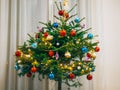 A small Christmas tree in a pot, decorated with balls, garlands Royalty Free Stock Photo