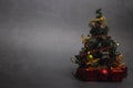 Small Christmas tree with presents and New Year`s red decorations on a dark background.