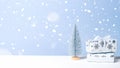 Small Christmas tree with two handmade gifts in snow on blue background. Christmas holiday banner, New Year greeting card mockup