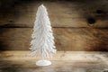 small christmas tree from white flocked wire against a rustic wooden background with large copy space