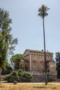 A small church near a palm tree in a park on a Villa Doria-Pamphili in Rome, Italy