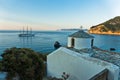 Small church and sailing ship at sunset in front of city harbor, Skopelos island