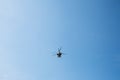 Small civil helicopter flies against a blue sky background