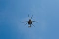 Small civil helicopter flies against a blue sky with clouds background