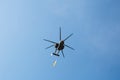 Small civil helicopter with Ukrainian flag flies against a blue sky with clouds background