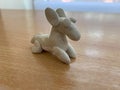 Small clay made white dog on a wooden table with a blurry background Royalty Free Stock Photo