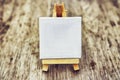 Small clean easel on wooden background. Abstraction for thoughts and ideas. White easel.