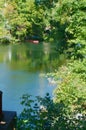 Small clean river with trees reflected and red canoe parked on bank