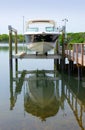 Small clean v-bottom bay motorboat on an electric lift on a wood dock Royalty Free Stock Photo