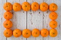 Small clementine oranges in a rectangular shape on a whitewashed wood background