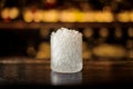 Small cocktail glass with ice pieces on the bar counter in the background of golden lights