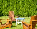 Small coffee table and wooden chairs on a in small cute green backyard Royalty Free Stock Photo