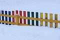 Small colored wooden decorative fence in a snowdrift of white snow Royalty Free Stock Photo