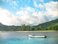 Small colorful boat anchored off a Seychelles beach with distant Royalty Free Stock Photo