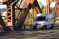 Small compact cargo mini van driving on the truss bridge