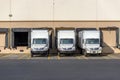 Small compact rigs semi trucks with box trailers standing in row at warehouse docks for loading cargo