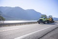 Small compact semi tip truck transporting multifunctional tractor driving on the road along Columbia River Royalty Free Stock Photo