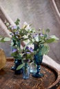 Small compositions of blue flowers and decorative greens in glasses and bottles of blue glass. Wedding floristry.