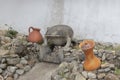 A small concrete frog sculpture in a dry fount with two red ceramic pots