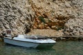 Small concrete molo near steep cliff in small cove with white fisherman motor boat. Adriatic sea, Croatia Royalty Free Stock Photo