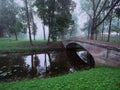 Small concrete old bridge over a small river in a town forest park in a fog. Mistry surreal calm mood. Relaxing atmosphere and