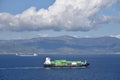 Small container ship sailing near sea coast close to Gibraltar. Royalty Free Stock Photo