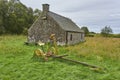 A small Cottage with an Antique Horse Drawn Hay cutter parked outside it, at Crombie Park near Dundee. Royalty Free Stock Photo