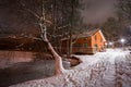 Small cottage house near lake at snowy night