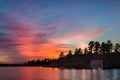 Small cottage in shadow on a lake at sunset. Royalty Free Stock Photo