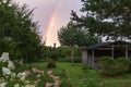 Small country house on a summer evening. Rainbow over the house. Beautiful sunset. Hydrangea flowers in the garden Royalty Free Stock Photo