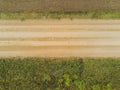 Small country road and freshly ploughed soil on one side and green meadow on the other. Aerial view Royalty Free Stock Photo