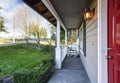 Small covered porch with white rocking chair and red front door.