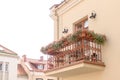 Small cozy balcony with outdoor furniture, lighting and flowers