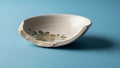 A small cracked ceramic bowl with a floral pattern on a blue background Royalty Free Stock Photo
