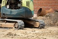 Small crawler loader digs in the park trench for laying pipes