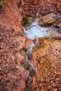 Small creek going through brown clay carving out patterns