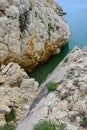 Small croatian shore cove hidden between steep cliffs with clear azure water and stony bottom, viewed from above