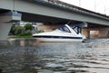 Cruise motor yacht sails under a concrete bridge