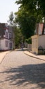 Small curved cobblestone street lined with houses with people walking away in the distance