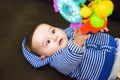 Small baby in body lies on his back in crib and holds toy in his hands. Royalty Free Stock Photo