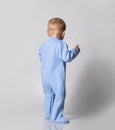 Small cute baby boy in blue warm comfortable jumpsuit standing and keeping balance, rear view