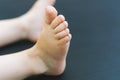 Small cute, baby feet on a dark background close-up. Beautiful bare feet of a Caucasian two-year-old child. Selective, soft focus Royalty Free Stock Photo