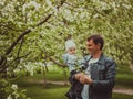 Small cute baby boy with his father walking in spring park outdoor. Man hold his little son on hands. Blooming trees in Royalty Free Stock Photo