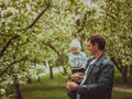 Small cute baby boy with his father walking in spring park outdoor. Man hold his little son on hands. Blooming trees in Royalty Free Stock Photo