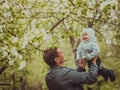 Small cute baby boy with his father walking in spring park outdoor. Man raises his little son on his hands. Blooming Royalty Free Stock Photo