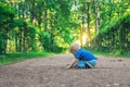 Small cute baby with nipple sits on the footpath in the dreamlike forest all alone. Little boy sitting on the ground. Royalty Free Stock Photo