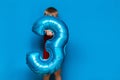 Small cute blonde boy on blue background holding foil-coated sphere baloon blue colour. happy birthday three years old Royalty Free Stock Photo