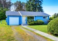 Small cute blue house with driveway and trimmed hedges.