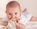 Small cute funny baby infant teething with face expression hands and fingers in mouth Royalty Free Stock Photo